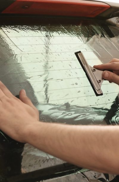 Worker applying tinting foil onto car window Worker applying tinting foil onto car window
